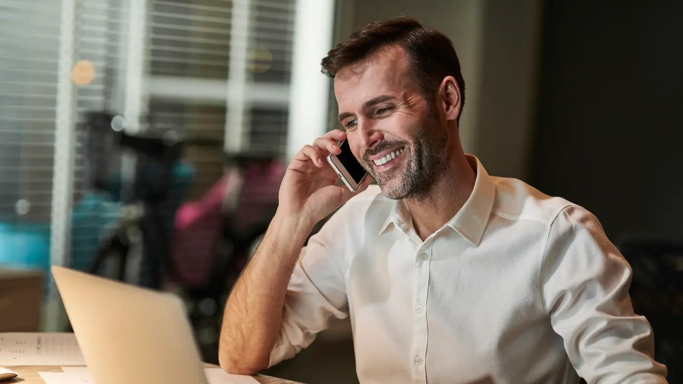 Dono de restaurante tranquilo operando o negócio pelo celular e laptop