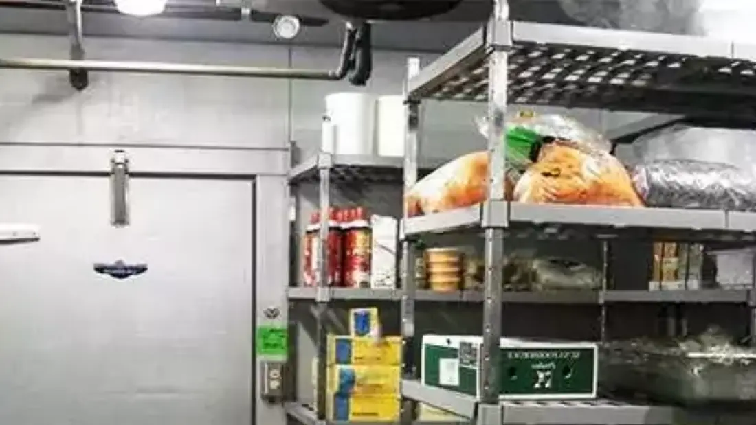 Câmara fria com insumos organizados em prateleiras de estoque